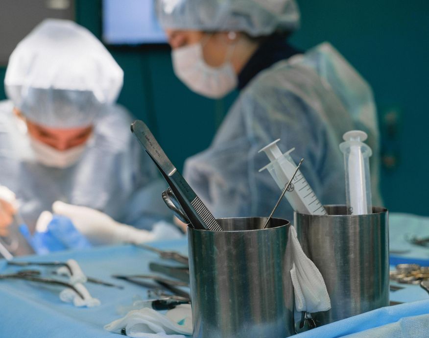Focused surgeons in an operating room performing surgery with medical instruments.