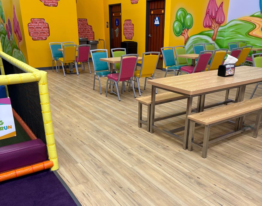 Cheerful child having fun in a colorful indoor ball pit playground, smiling widely.